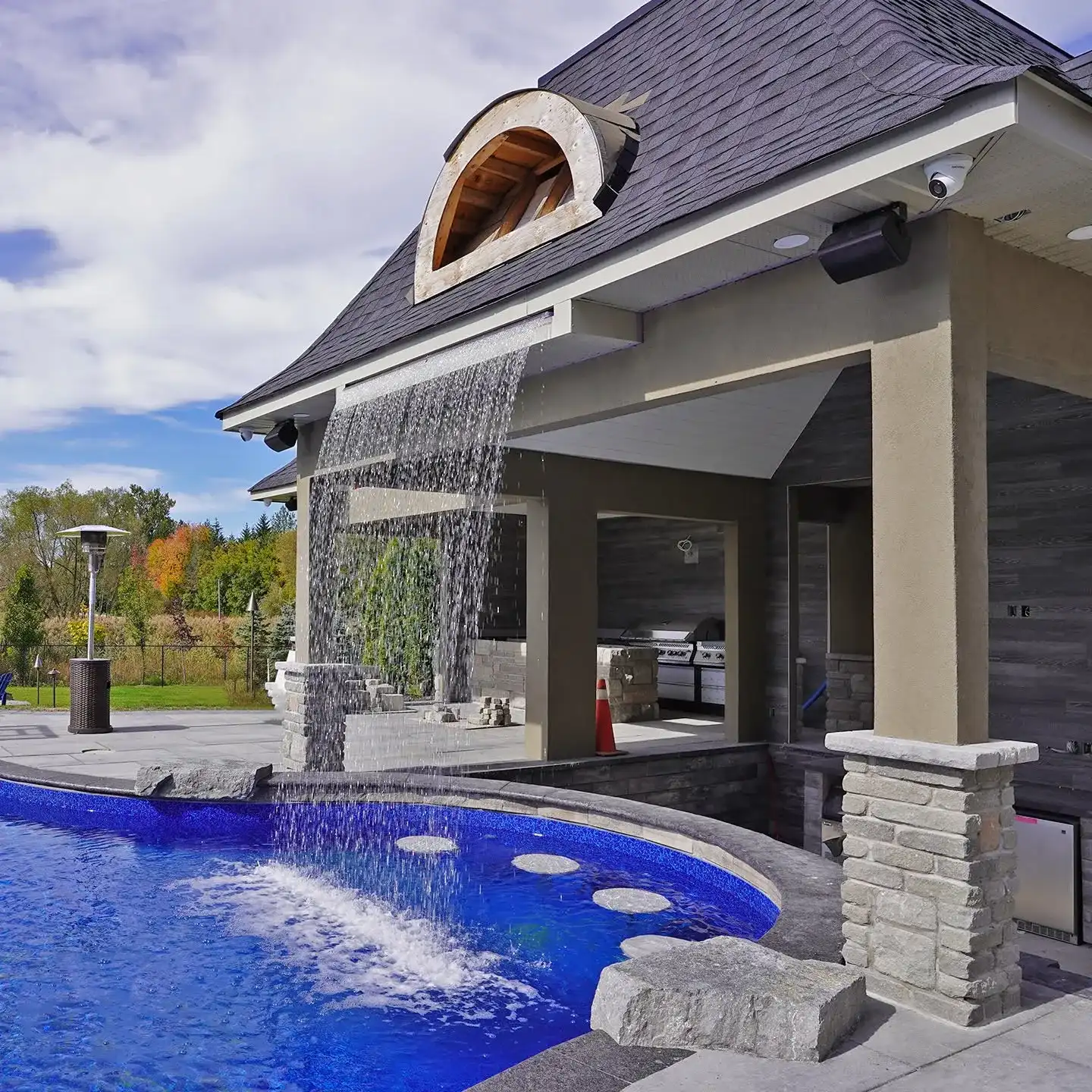 Covered pavilion beside a blue pool with a waterfall