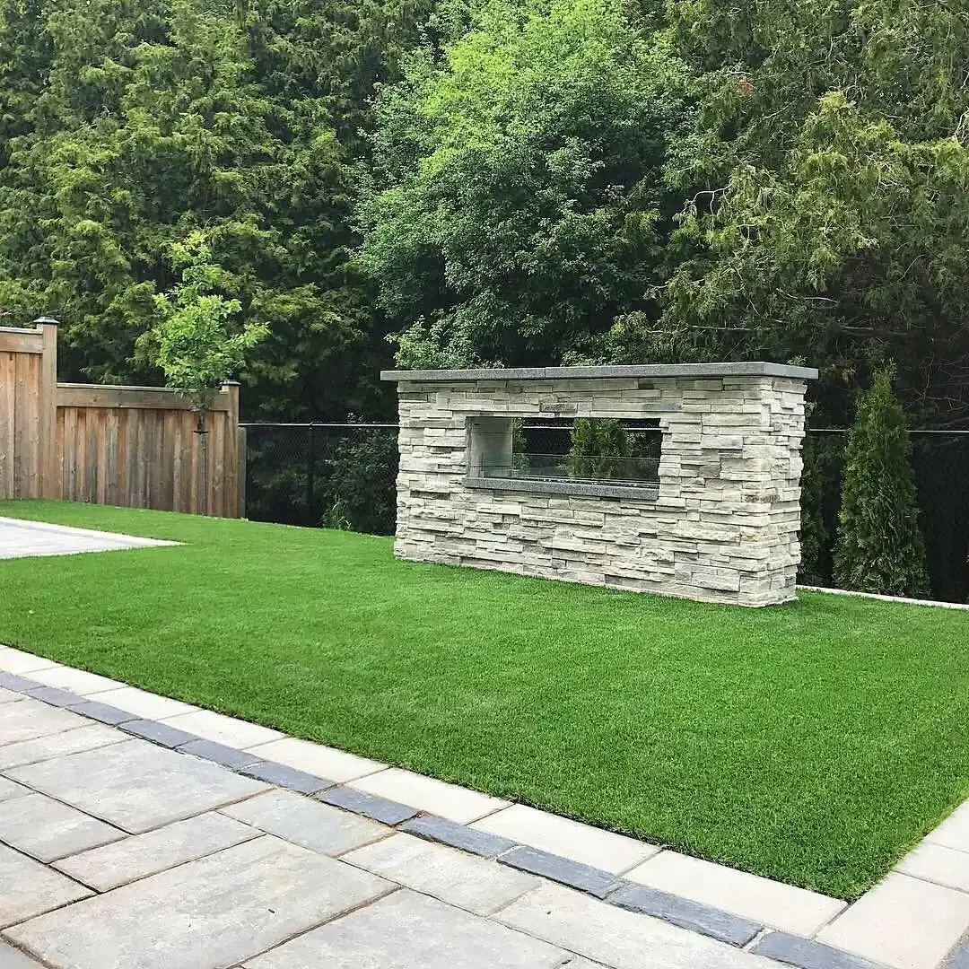 Stacked-stone linear fireplace on a turf lawn