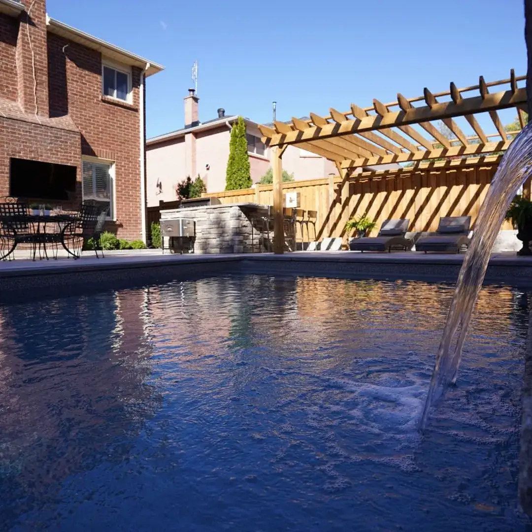 Pool with a laminar water jet and wood pergola