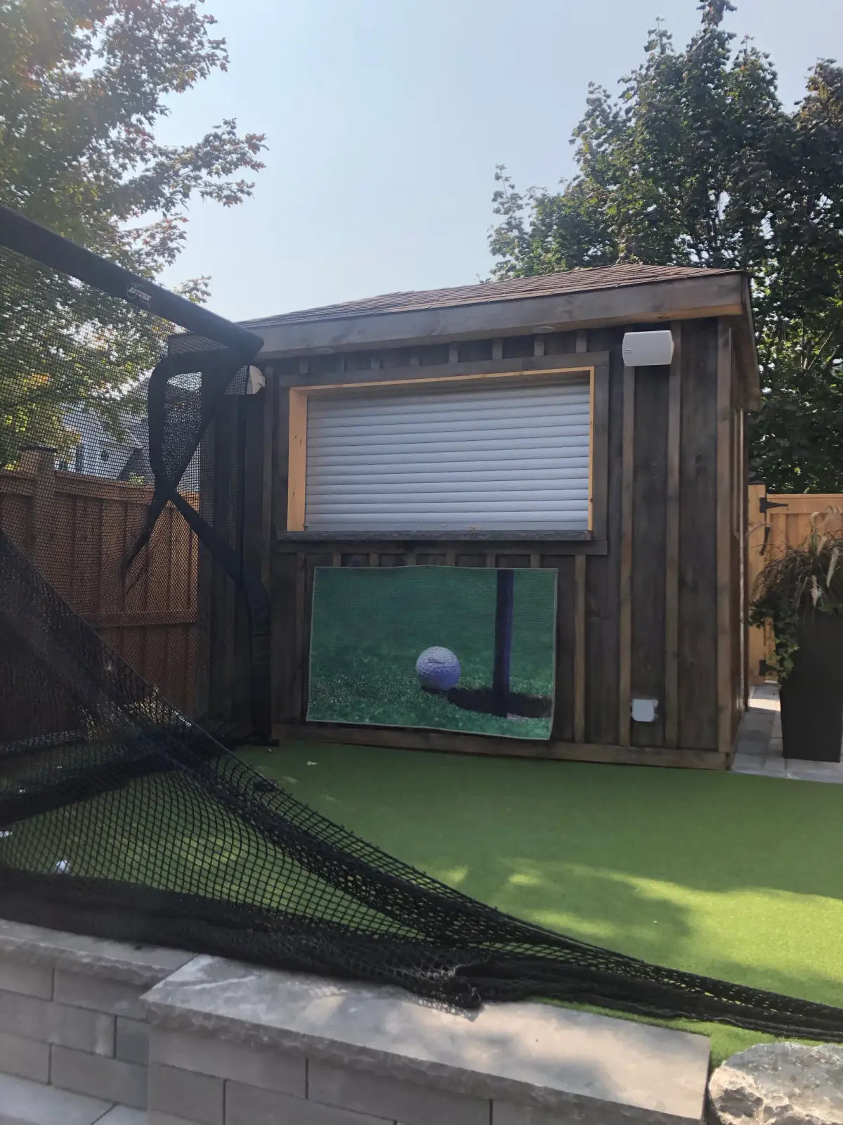 Backyard golf simulator with netting and putting turf